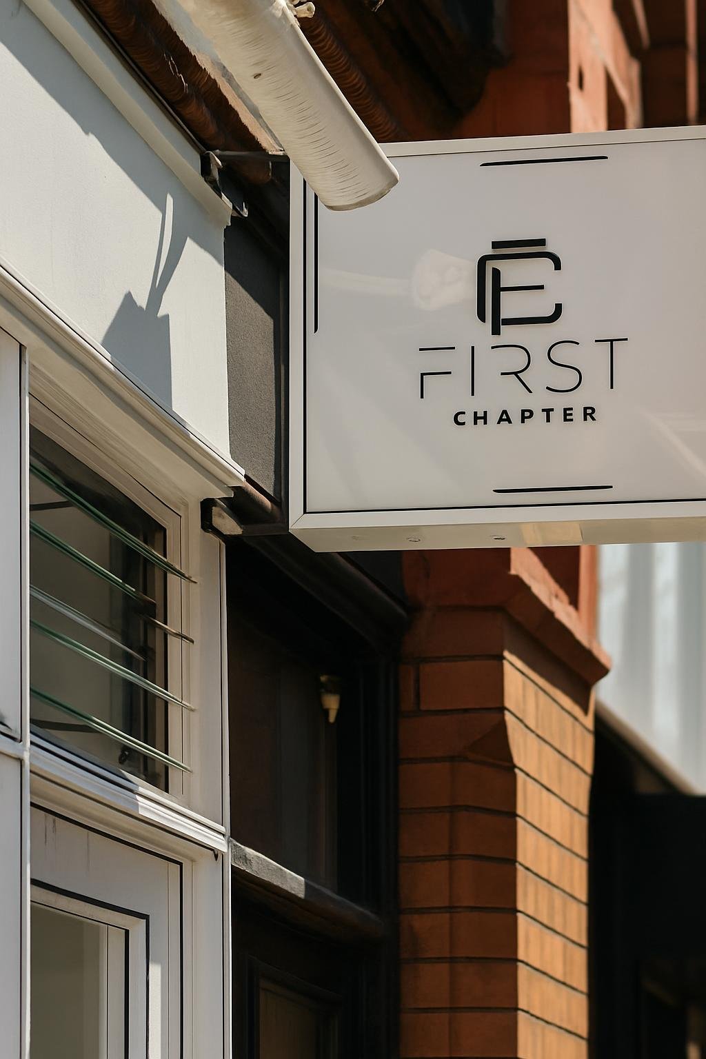 The First Chapter sign — a circular monogram and wordmark on a white awning above the shopfront on Fade Street
